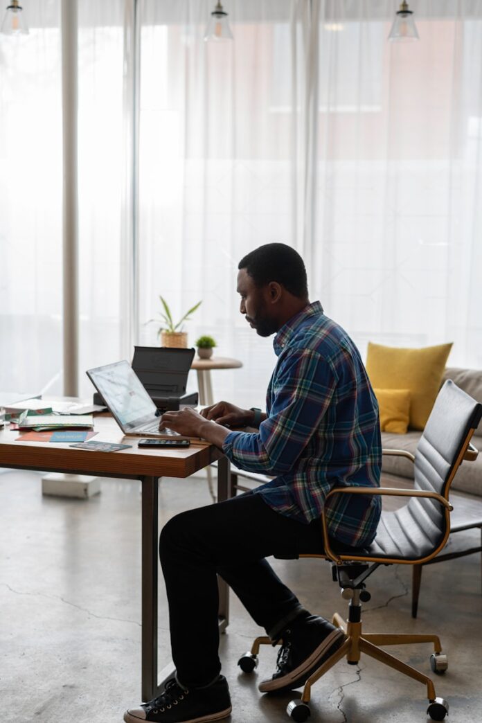 Photo by LinkedIn Sales Solutions man in blue and white plaid dress shirt sitting on chair using laptop computer
