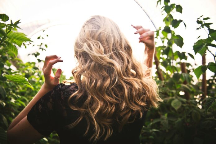 Photo by Tim Mossholder blonde haired woman in black top surrounded by tall plants