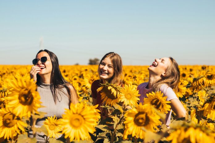 Photo by Antonino Visalli woman in white and black striped shirt standing on yellow sunflower field during daytime