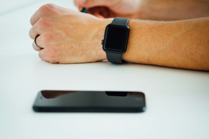 Photo by Dose Media black smartphone near person's hand wearing black smartwatch