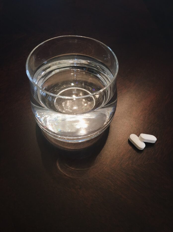 Photo by pina messina two oval white medication tablets on brown surface