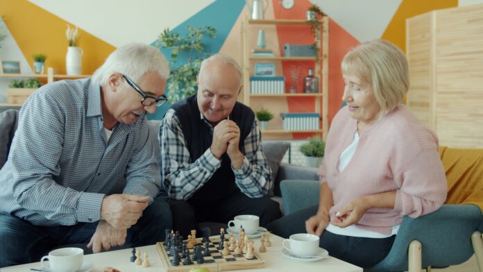 Seniors playing chess together on a sofa.