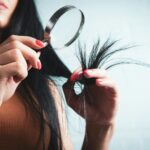 집에서 시작하는 건강한 모발 관리, 최신 트렌드와 실천 팁 Woman examining split ends of hair with magnifying glass