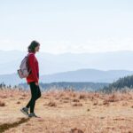 걷기 열풍, 일상 속 건강 지키는 작은 변화가 만든다 a man with a backpack walking across a dry grass covered field
